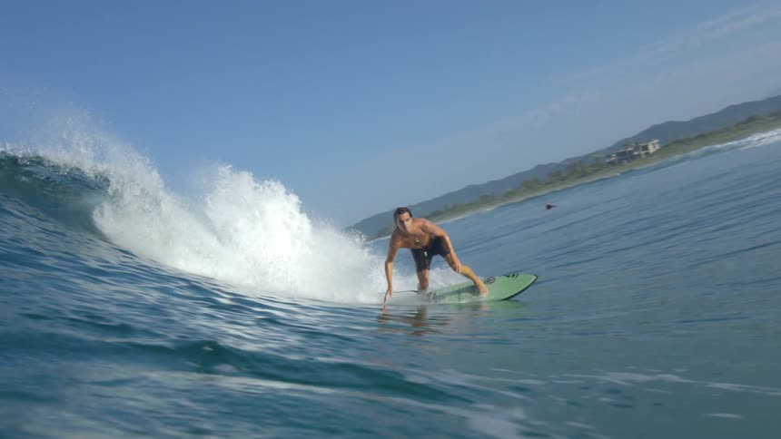 Male surfer rides a big wave on a clear day