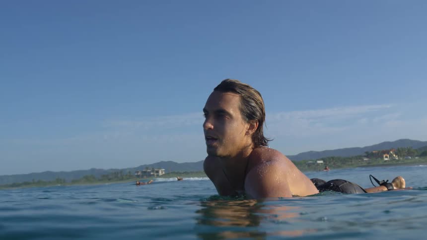 Young fit man swimming in the calm ocean waters over a surf board