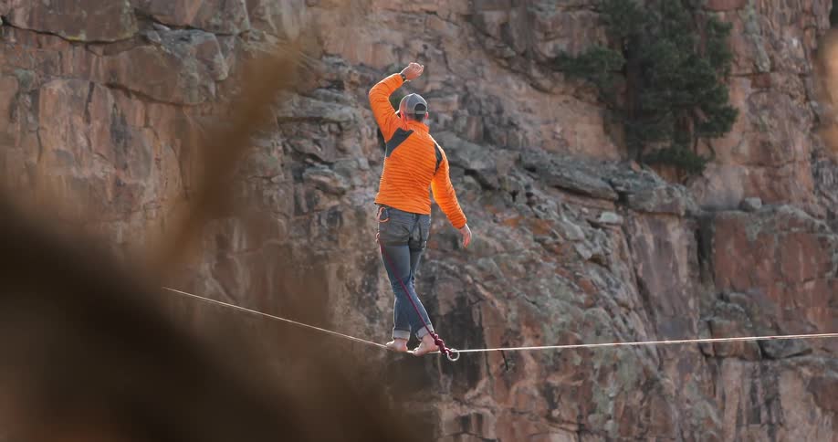 A woman walks a tightrope stretched out over a gorge