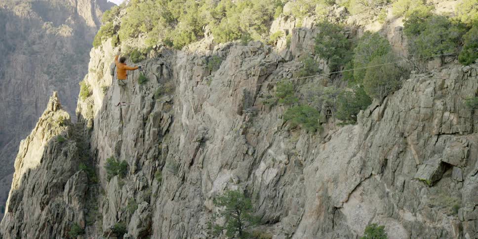 Man walking on tightrope over a canyon