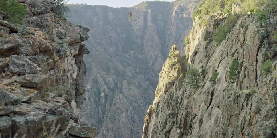 Person walking on a tightrope over a steep canyon