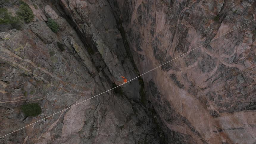 A person is walking over a tightrope over a large cliff