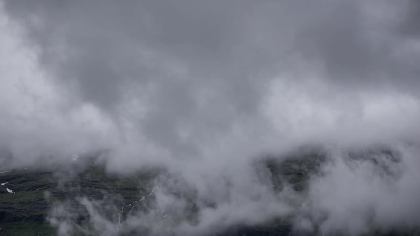 Clouds form and swirl above a mountain landscape in Norway