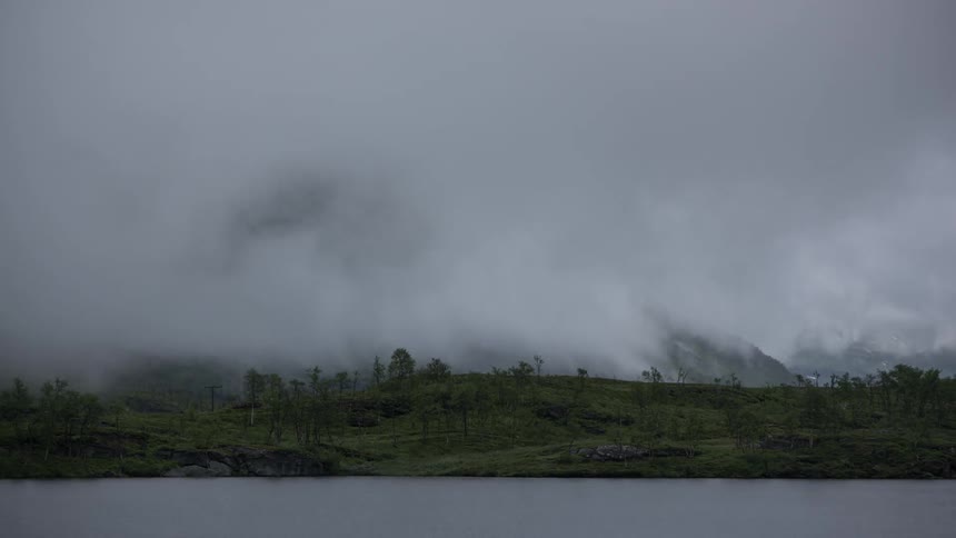 Low clouds flowing up and around a large mountain