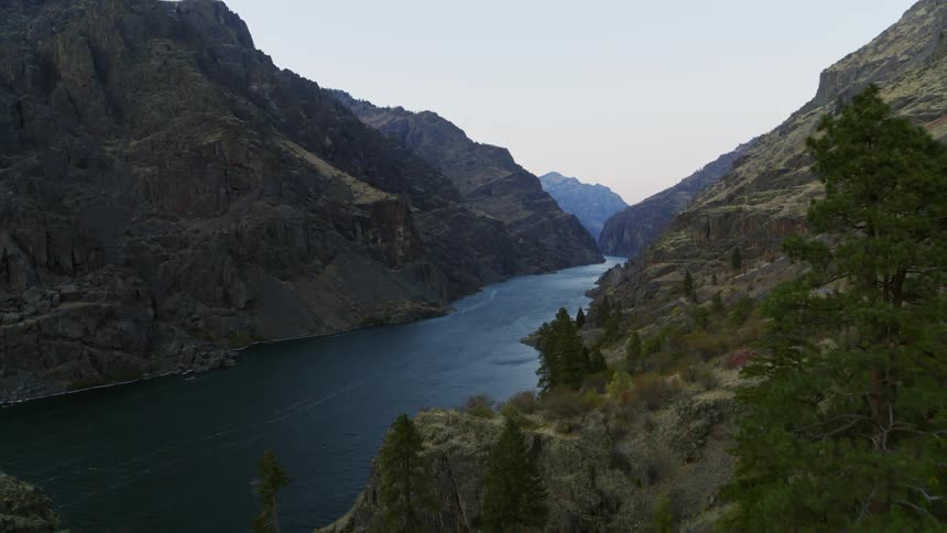 Descending into a deep river valley surrounded by tall and dramatic rocky mountains