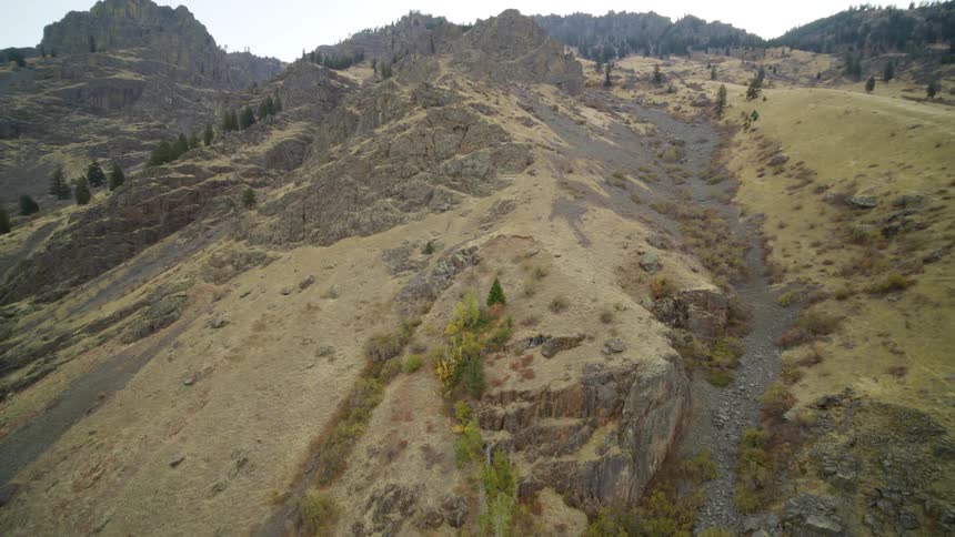 Tilt up pullback reveal of a steep and rocky mountain slope