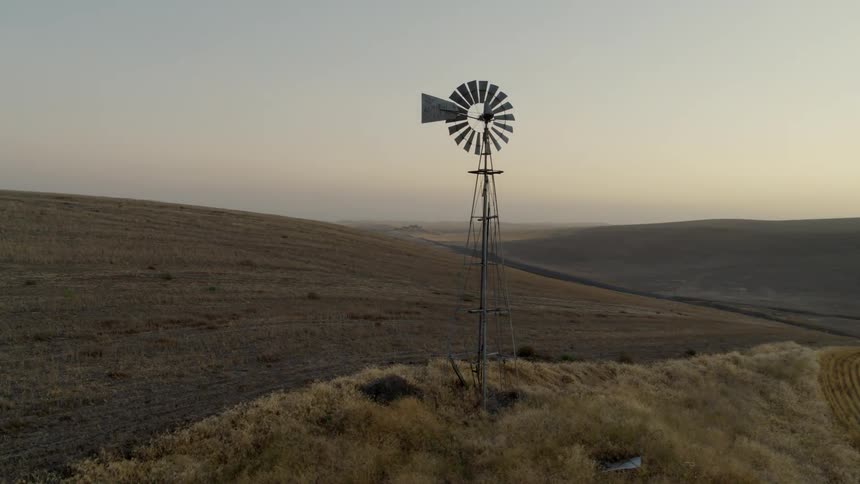 Orbiting around an old windmill along endless hills of rural farmland