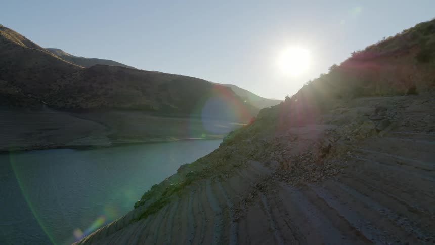Revealing a depleted mountain lake from behind its rocky shoreline