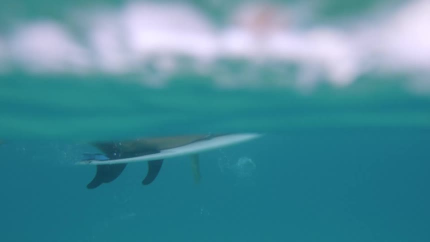 Blonde female surfer paddles on the surfboard in the water