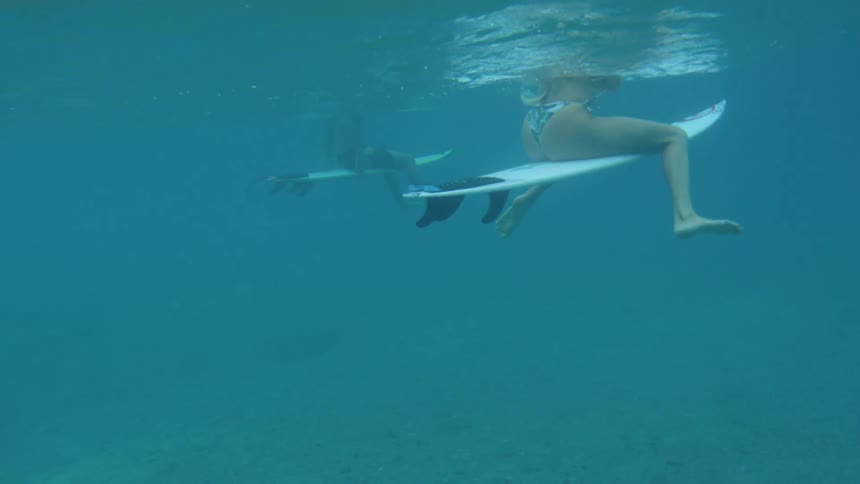 Woman win bikini and man sit on surfboards in the sea water