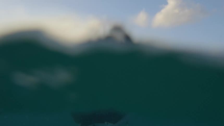A man paddles his surfboard in the ocean