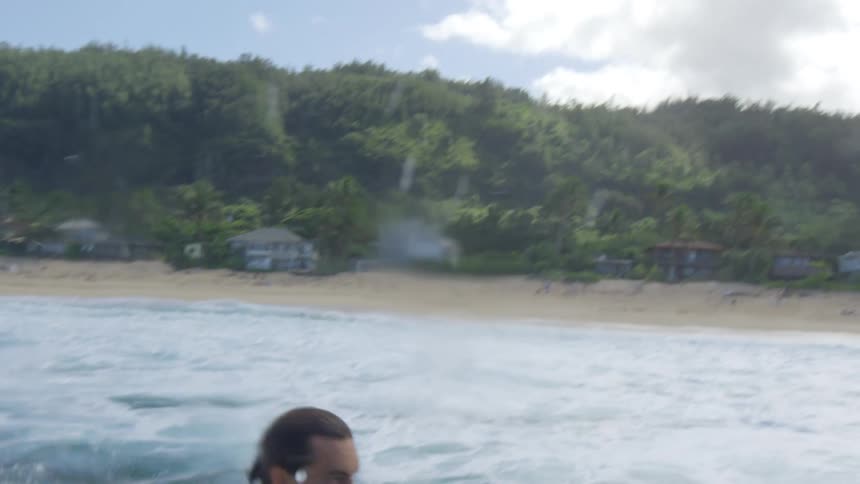 Male surfer with black swimming shorts rides a wave on a white surfboard
