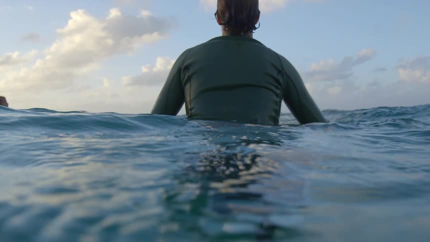 A man sitting on his surfboard in the water