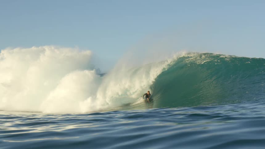 Surfers ride a huge wave on a clear day
