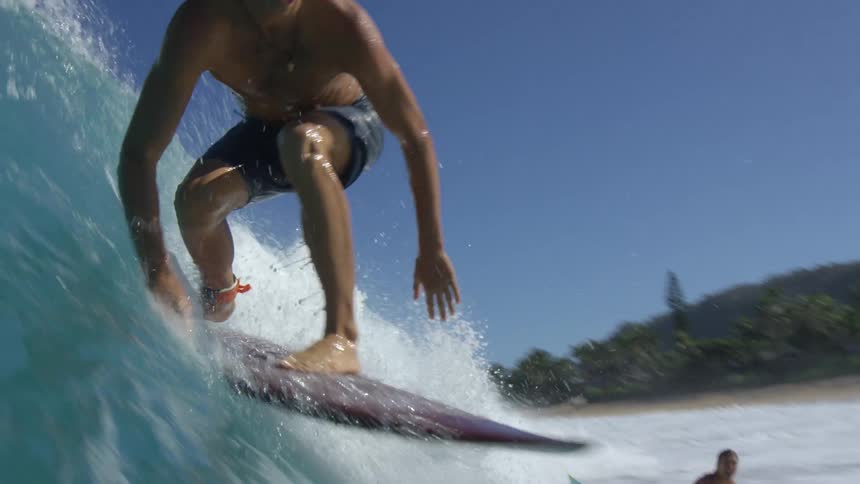Three surfers ride on a wave on a surfboards on a sunny day