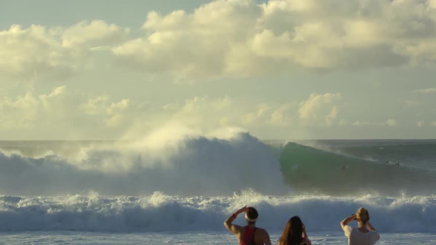 Three people watching the waves roll in