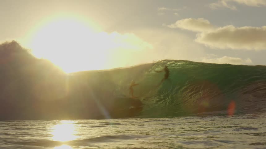 Two surfers rode a wave in the ocean during a bright and sunny day