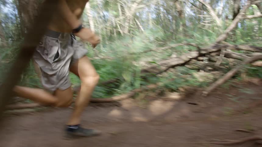 Man with shorts and black running shoes runs on dirt road in the woods