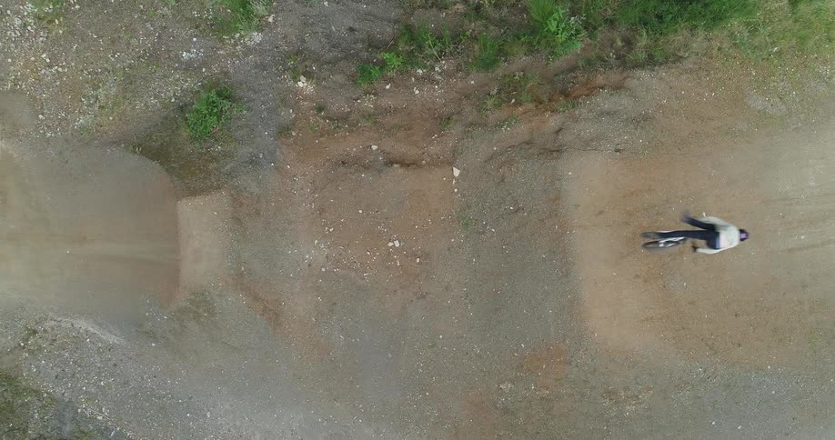 Person on a trick bike rides up a dirt slope and does a trick in midair lands it and rides away