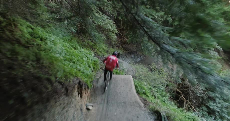 Cyclist driving a mountain bike jumps the gap on a road on the mountain