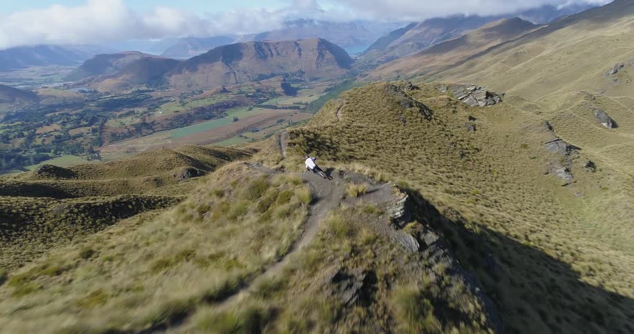 An aerial view of a person mountain biking on a trail on top of a hill