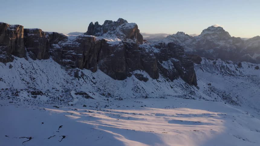 Aerial view of the snow covered peaks of a mountain range at sunset