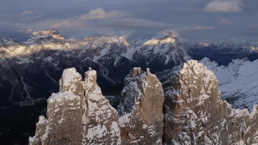 Snow covered jagged mountain peaks with a bar of sunlight on the farthest mountain range