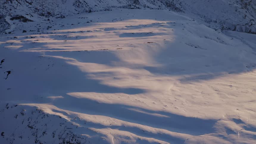 Sunlight hits snowy area at the bottom of a mountain like slope