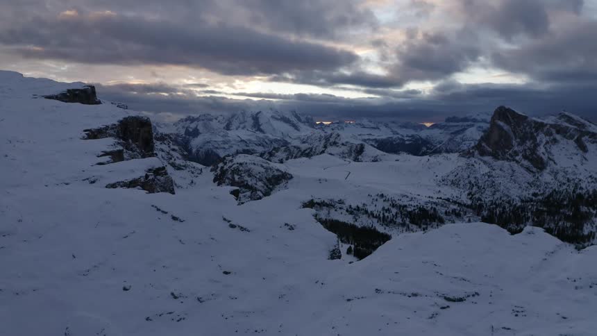 Cliff overlooking mountains covered at snow at dusk