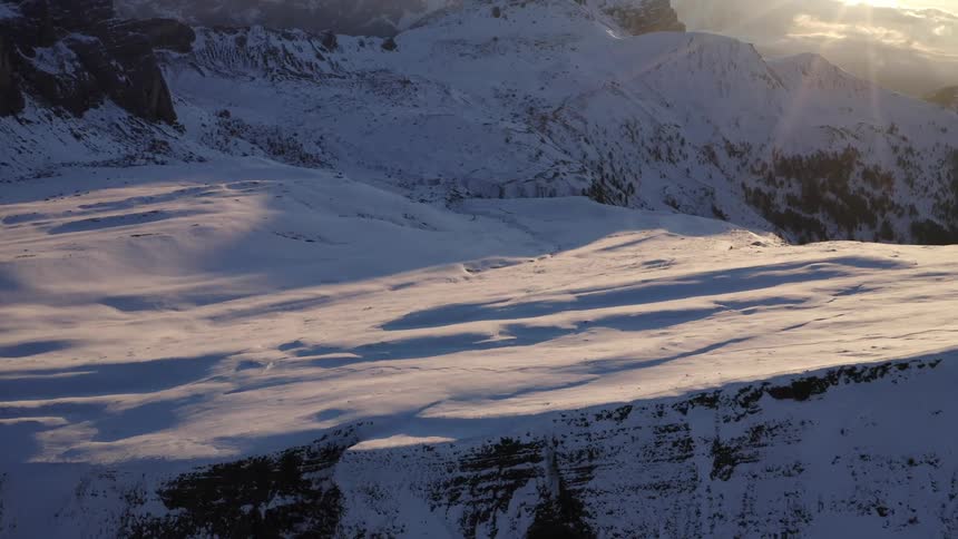 Snow covered mountains and peaks among a bright rising sun
