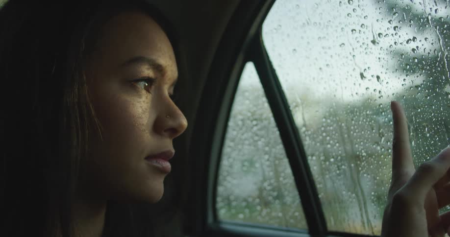 A woman is sitting in a car while its raining