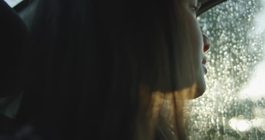 A woman is sitting in a car while looking out the car window