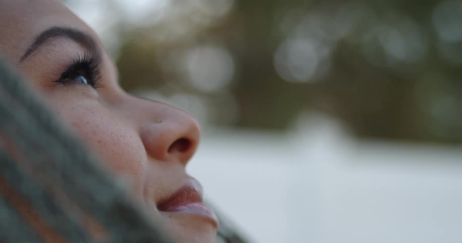 Close up of the face of a woman resting in a hammock outdoors