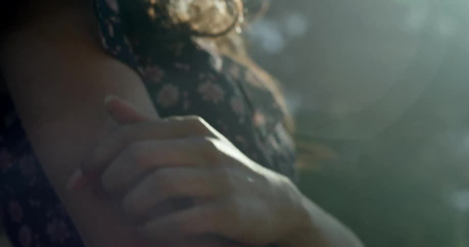 A woman in the sunshine rubs her arm