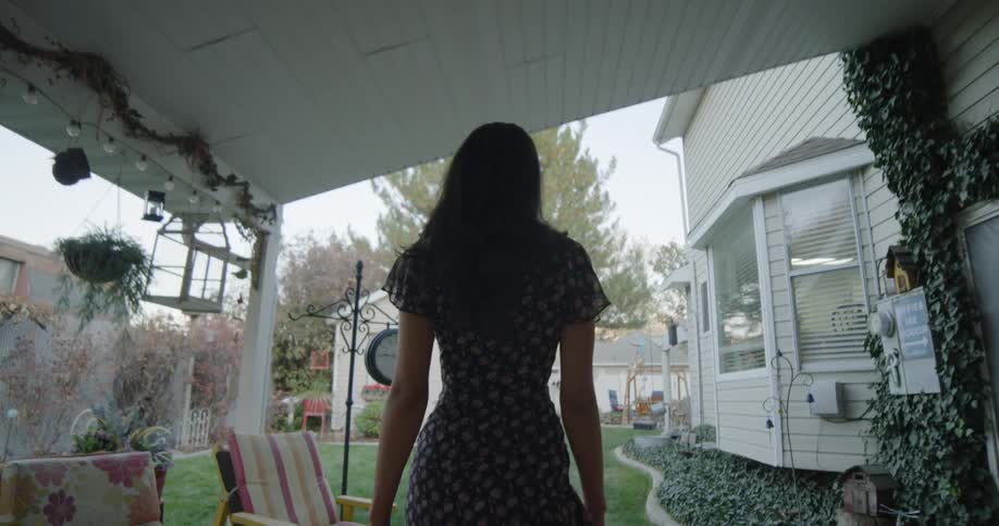 Woman with dark hair and a dress wanders around in the backyard