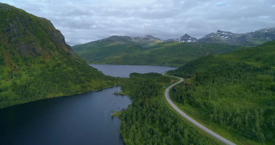 Car driving on the road through the forest next to the lake on the mountains