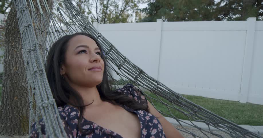 A woman smiles while swinging in a hammock