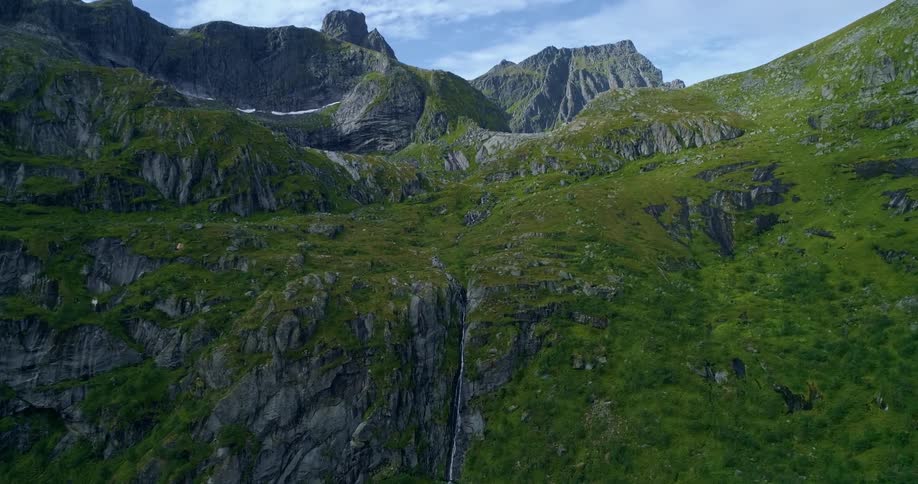 A cliff high in a stone mountain range covered in grass on a sunny day