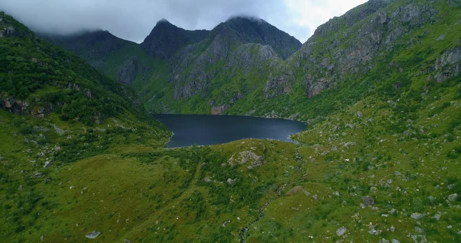 An aerial view of a mountain range with a lake at the base