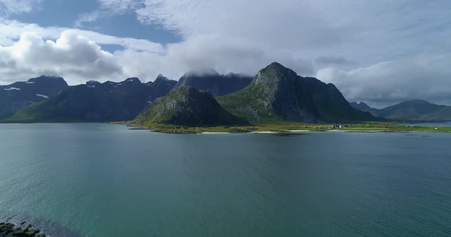 An aerial view of a lake and mountains with a cloudy sky during the day