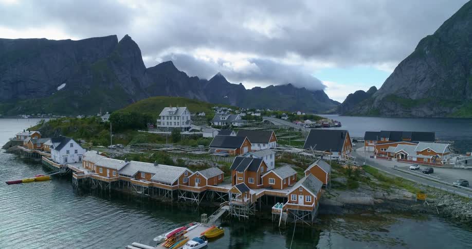 A small lakeside village surrounded by mountains on an overcast day