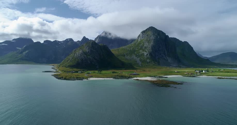 A flatland below a mountain on the coast of a landmass on a cloudy day