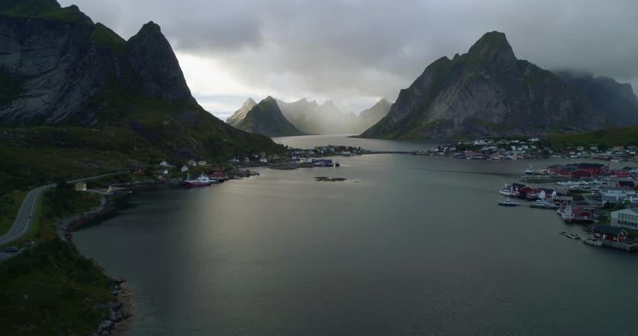 Coastal town on an island next to a large body of water leading out towards the ocean surrounded by mountains