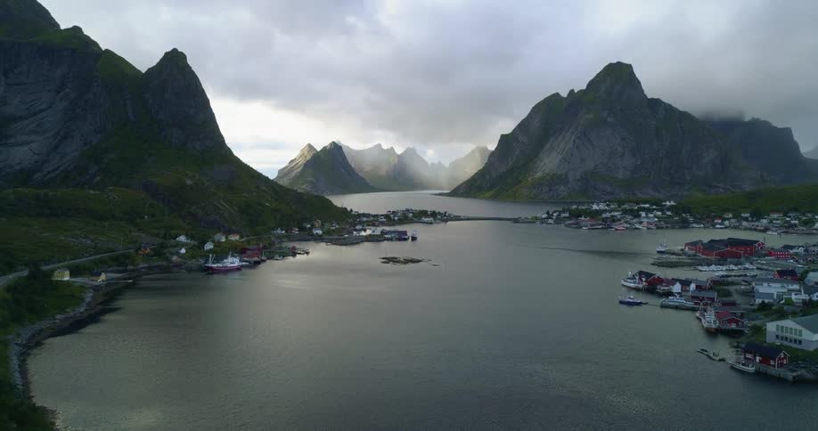 Aerial view of a town on a body of water with mountains and clouds