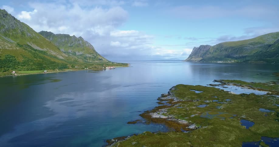 Islets and large islands out in a remote location surrounded by ocean with homes along the shore during the daytime