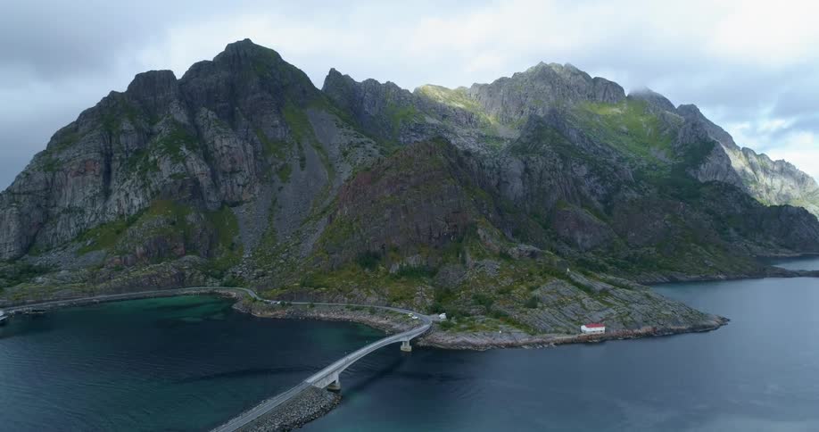 A landscape view of cars driving over a bridge towards mountains on an island
