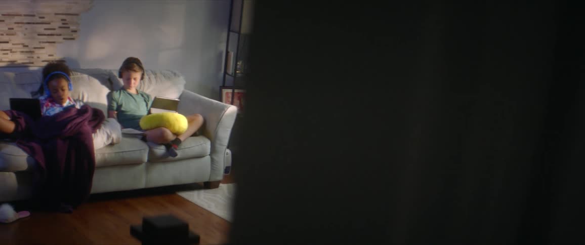 Two people sit on a couch relaxing during the day