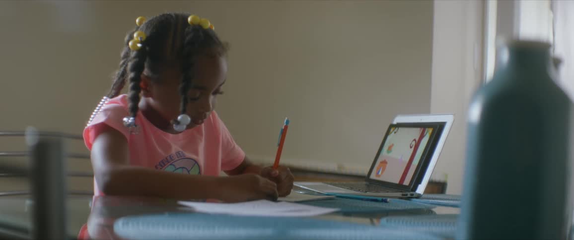 Little girl doing homework with a laptop on a table at home
