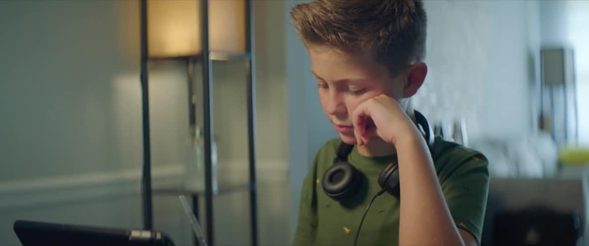 A young boy at home sits in front of a computer and does homework