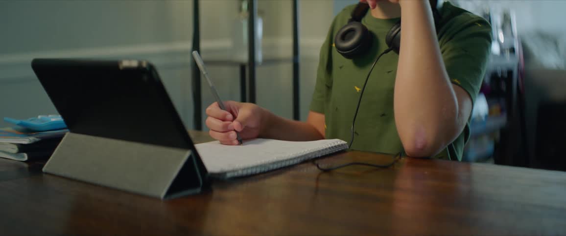 A child sits at home and does school work in front of a tablet